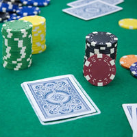 Striped dice poker chips on a green felt poker table with play cards.