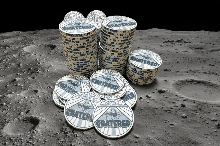 Stacks of 'Cratered' custom poker chips on a wooden surface with acrylic chip rack in background. 
